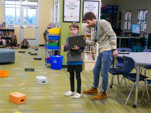 teacher helping student with robot